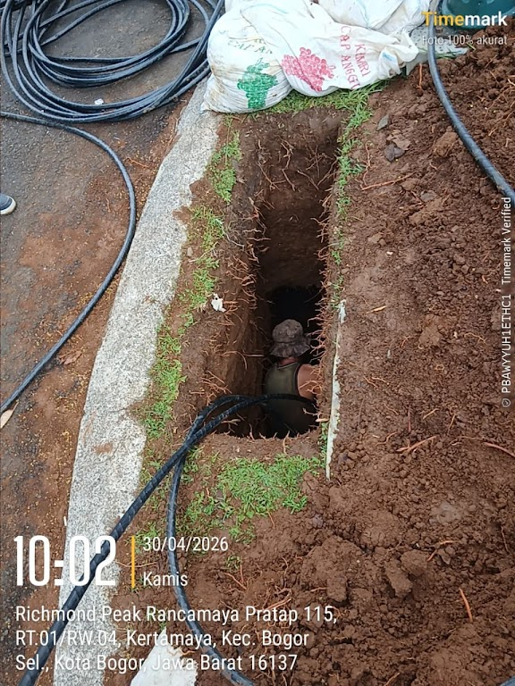 Pekerja memasukkan kabel ke lubang pit sebelum proses penarikan jalur bawah tanah
