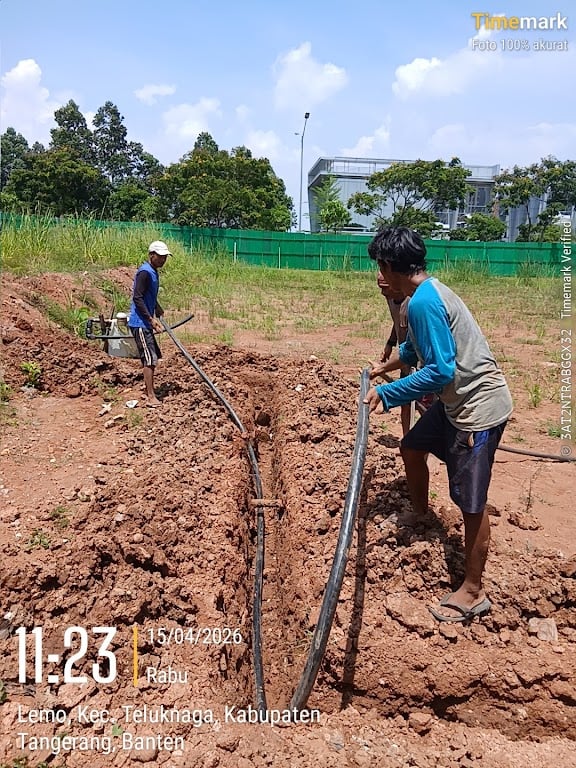Pekerja menarik gulungan kabel listrik PLN ke dalam sistem penanaman sepanjang trench galian