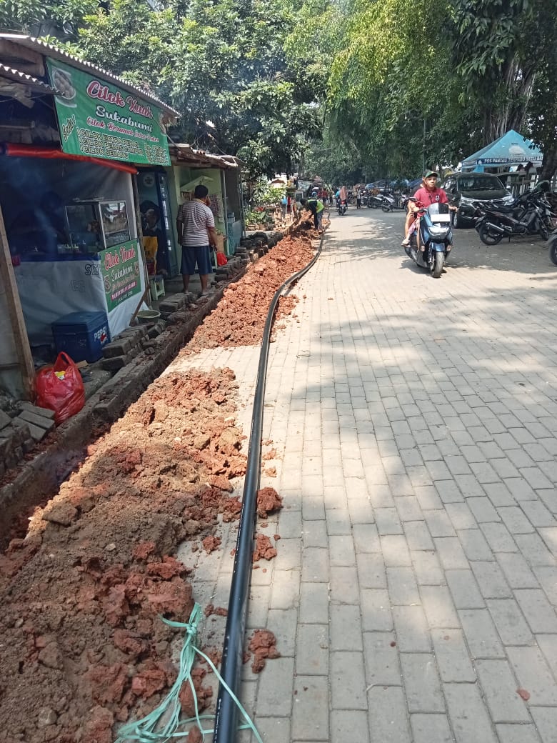 Pekerja merapikan galian di tepi paving block.