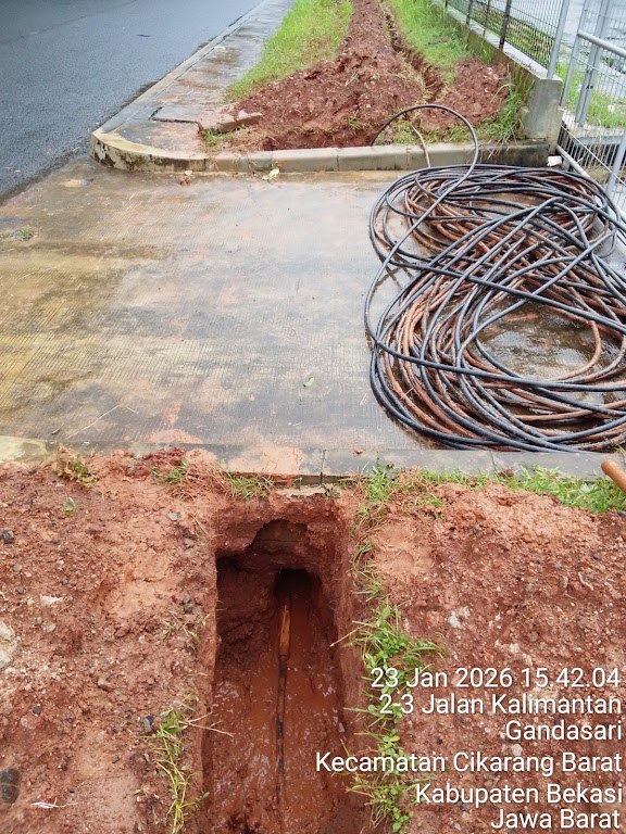 Lubang pit entry dengan kabel siap untuk ditarik melalui jalur boring di bawah jalan